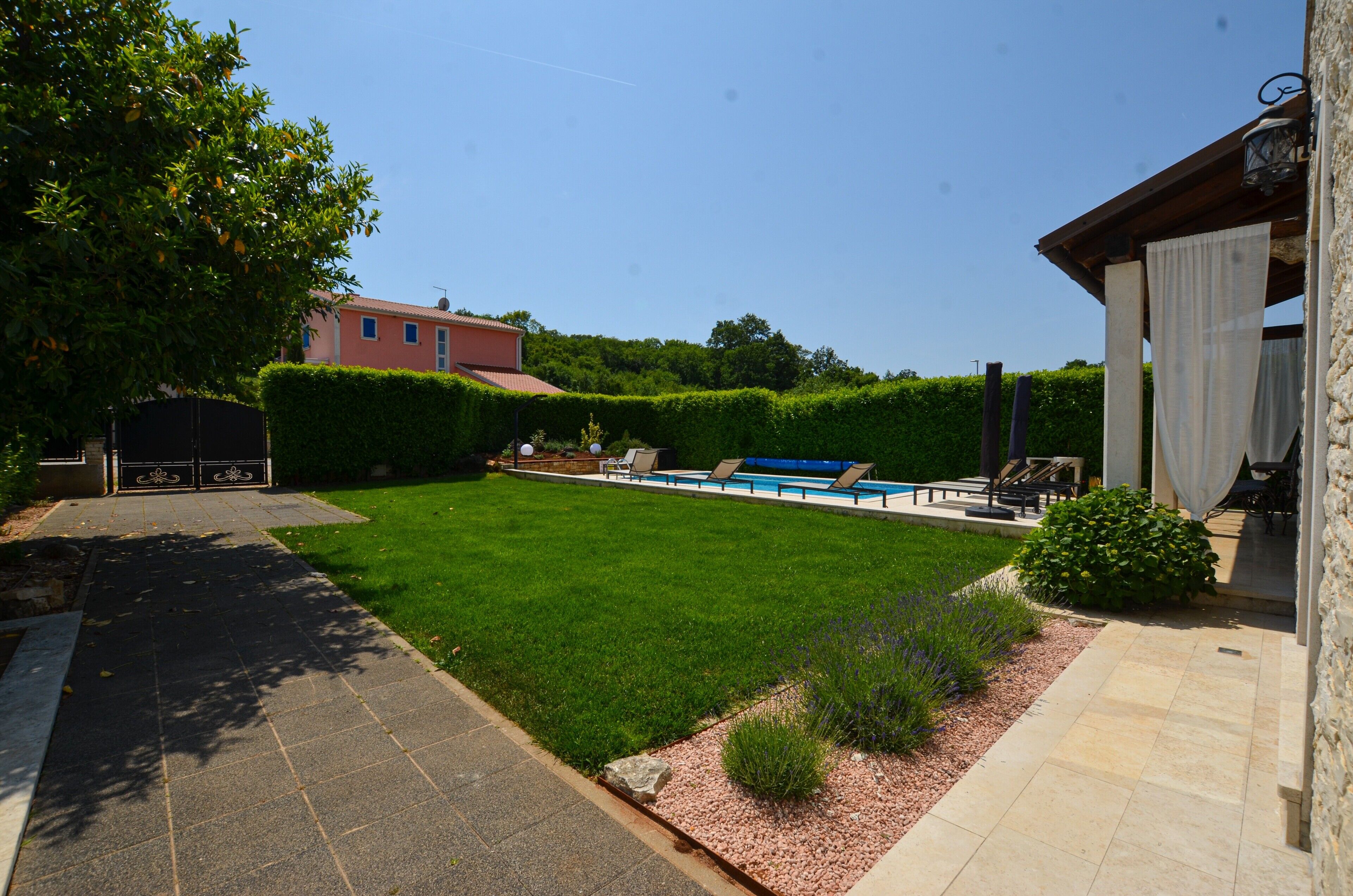 Un jardin bien entretenu avec une piscine, un espace patio aménagé avec des sièges et une pelouse soigneusement taillée.