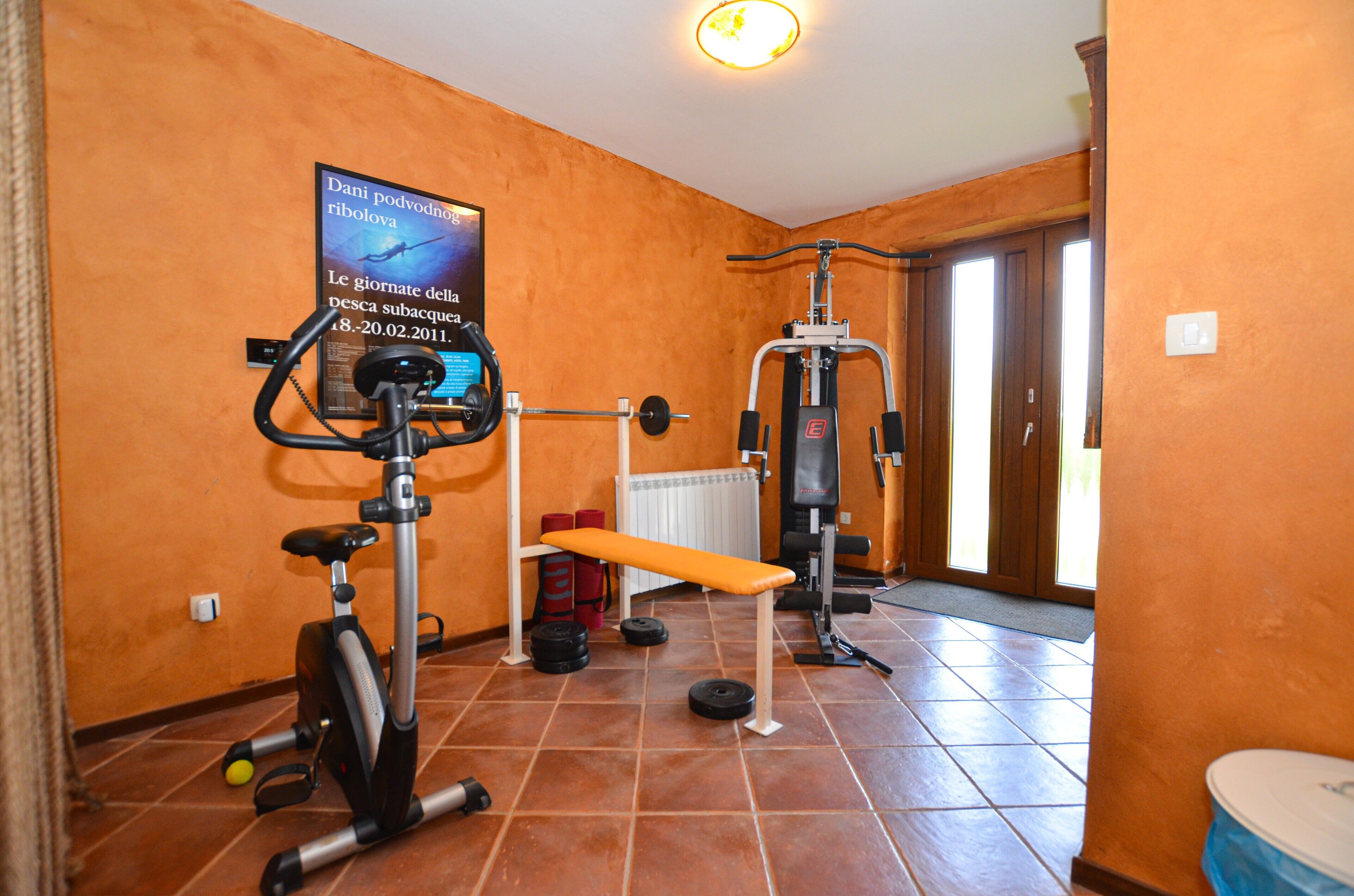 Ein Heimfitnessraum mit Trainingsgeräten, einer Bank und einem Poster an der Wand.