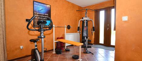 Ein Heimfitnessraum mit Trainingsgeräten, einer Bank und einem Poster an der Wand.
