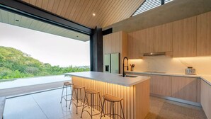 Una cucina moderna con una grande isola, sgabelli da bar e vista su del verde.