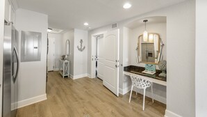 A modern kitchen with a refrigerator, a dining area with a white chair, and a countertop with a mirror and decorative items. - Waterfront, Harbourside, Water Park, Beach, #5516 (Indian)