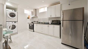 Una cocina moderna con electrodomésticos de acero inoxidable, armarios blancos y una mesa de comedor de vidrio.