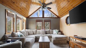 Una sala de estar acogedora con un sofá modular, una mesa de centro y un televisor en la pared.