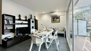 Una sala de estar moderna con comedor, que incluye un televisor de pantalla plana, una estantería y un cuadro en la pared.