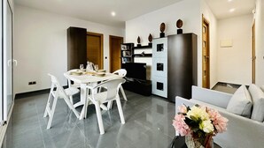 Una sala de estar moderna con comedor, un sofá y una mesa baja con flores.
