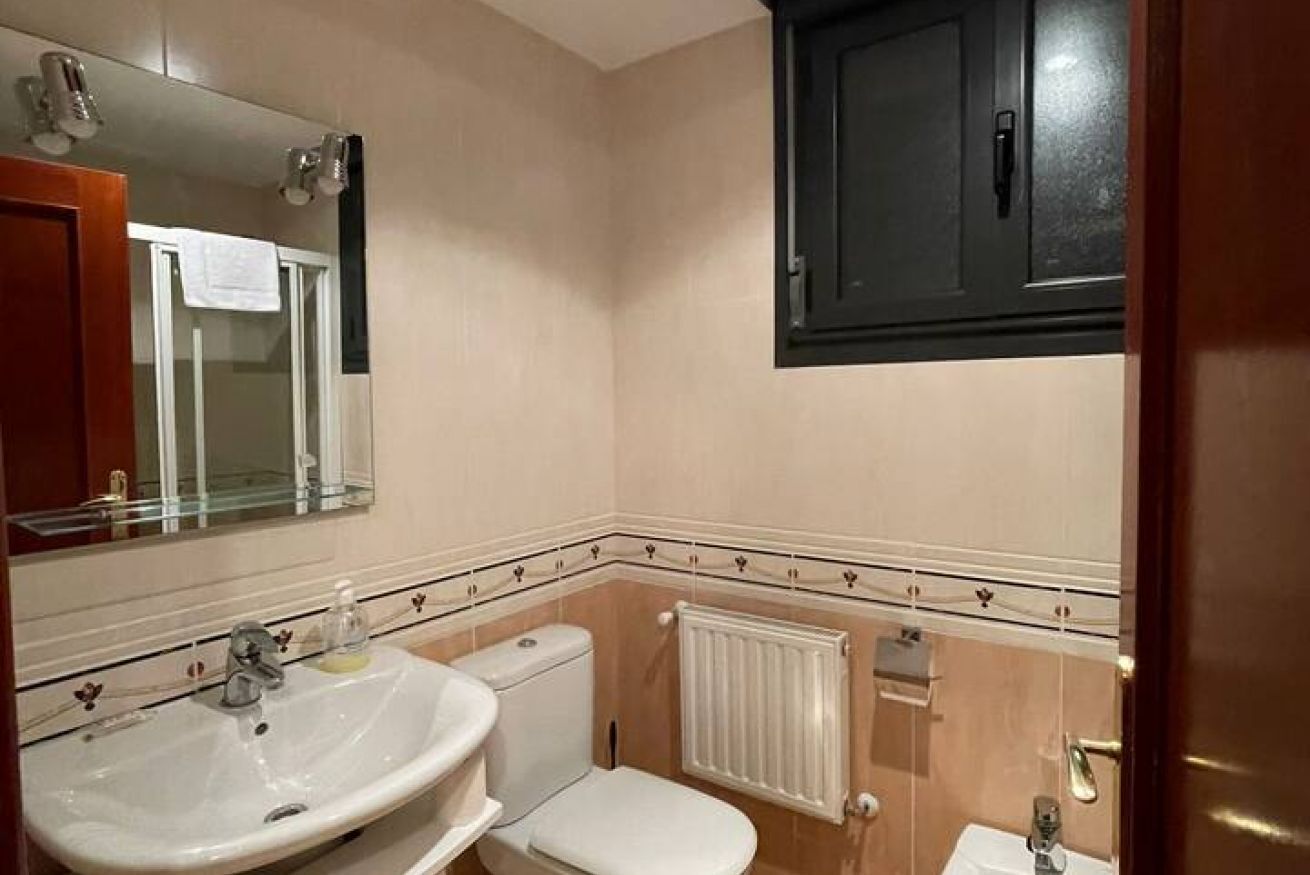 A bathroom with a sink, toilet, and mirror.