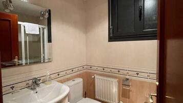 A bathroom with a sink, toilet, and mirror.