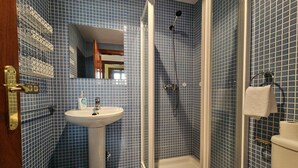 A bathroom with a sink, mirror, and shower.