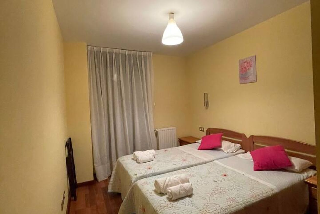 Una habitación con dos camas, un radiador, una cortina y un aparato de luz.