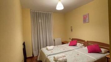 Una habitación con dos camas, un radiador, una cortina y un aparato de luz.