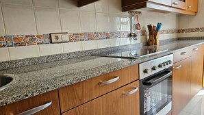 A kitchen with wooden cabinets, a granite countertop, a built-in oven, and a backsplash with patterned tiles. - The Llaneces Lookout 24A02 by R2R Consulting (Arenas de Cabrales)