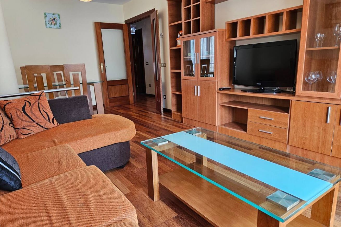 Un salon avec une table basse en verre, des meubles en bois, un téléviseur et un canapé.