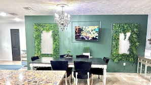 A dining area with a green wall, a chandelier, and a TV mounted above the table. - Unique space with lots of details! (Seffner)