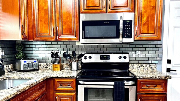 A kitchen with wooden cabinets, a microwave, a stove, and a dishwasher. - Unique space with lots of details! (Seffner)