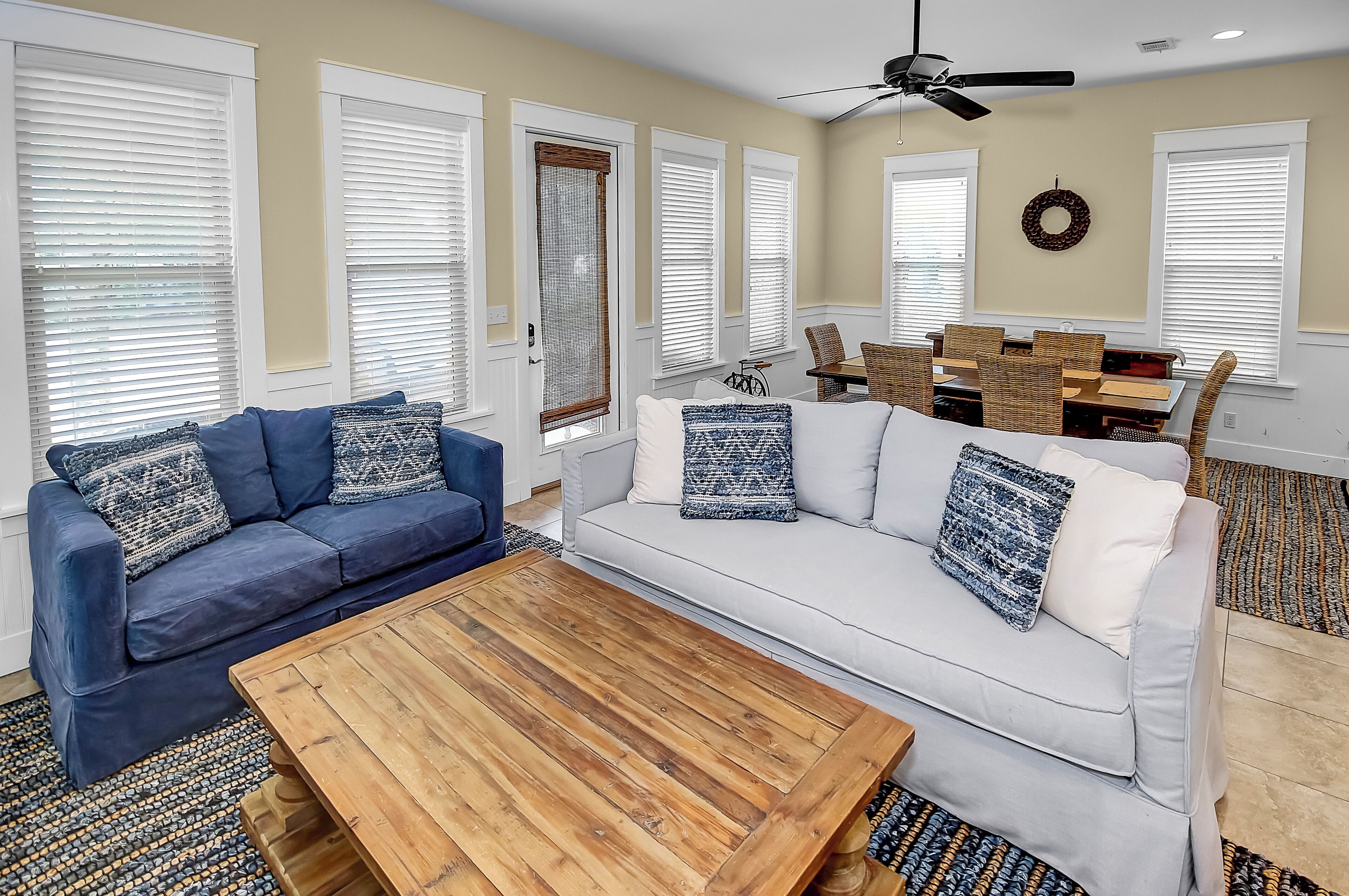 A living room with a blue sofa, white sofa, and a wooden coffee table.