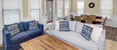 A living room with a blue sofa, white sofa, and a wooden coffee table.