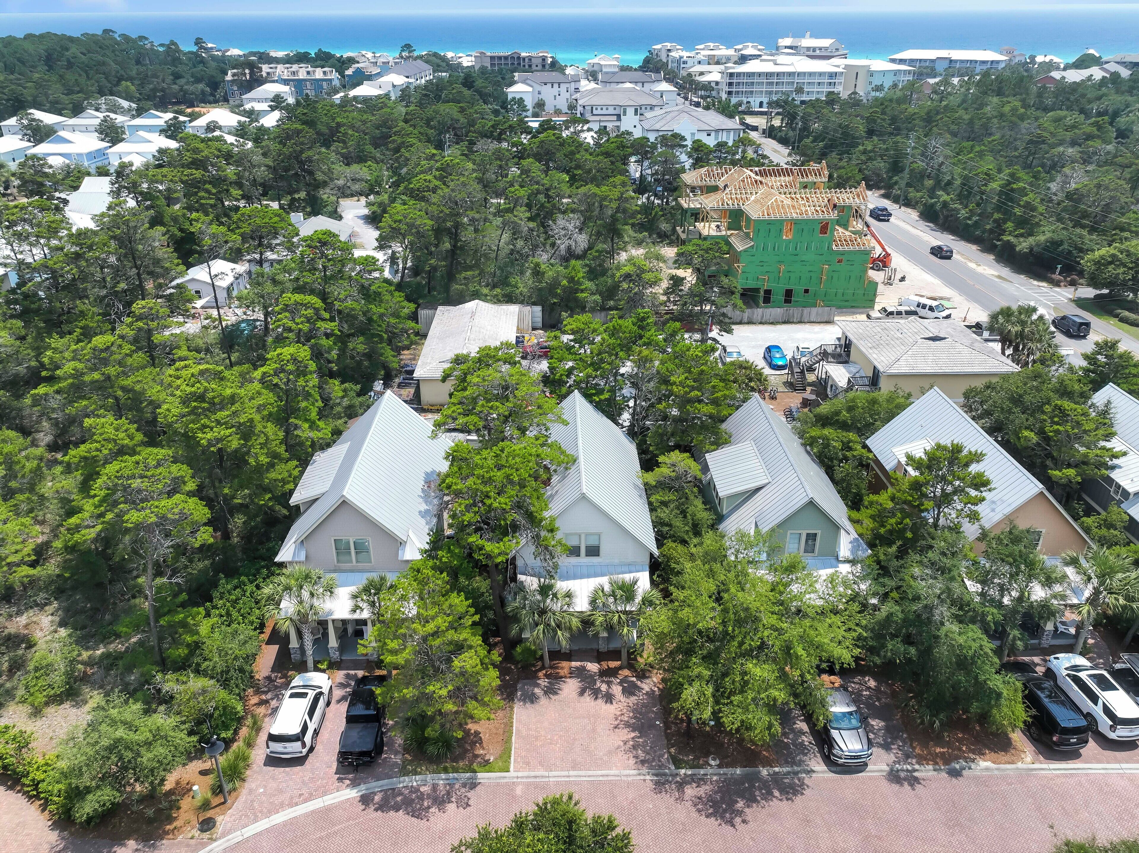 An aerial view of a residential area with houses, a green building under construction, and a road with parked cars.