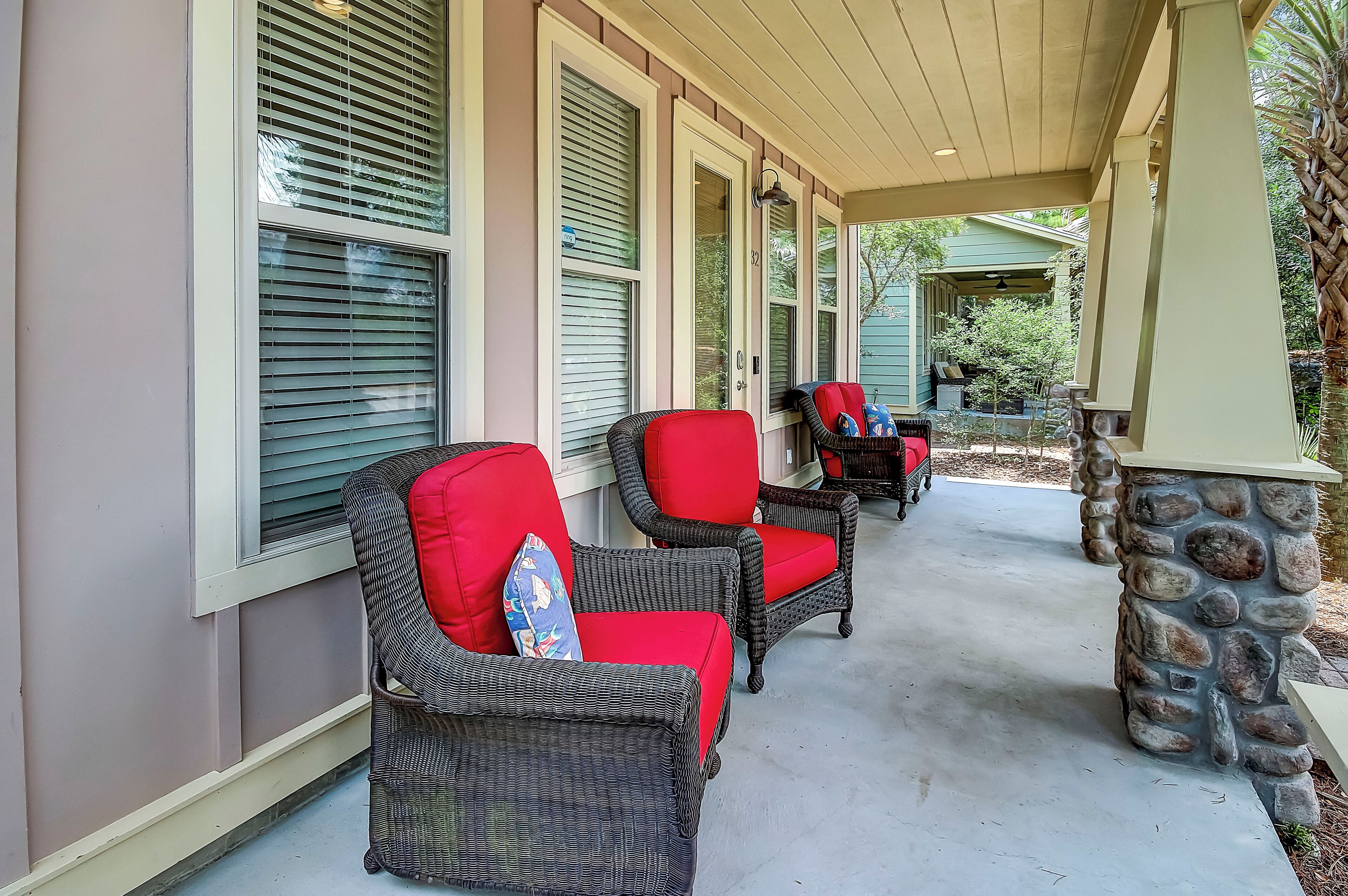 A covered porch with wicker chairs and a stone pillar.