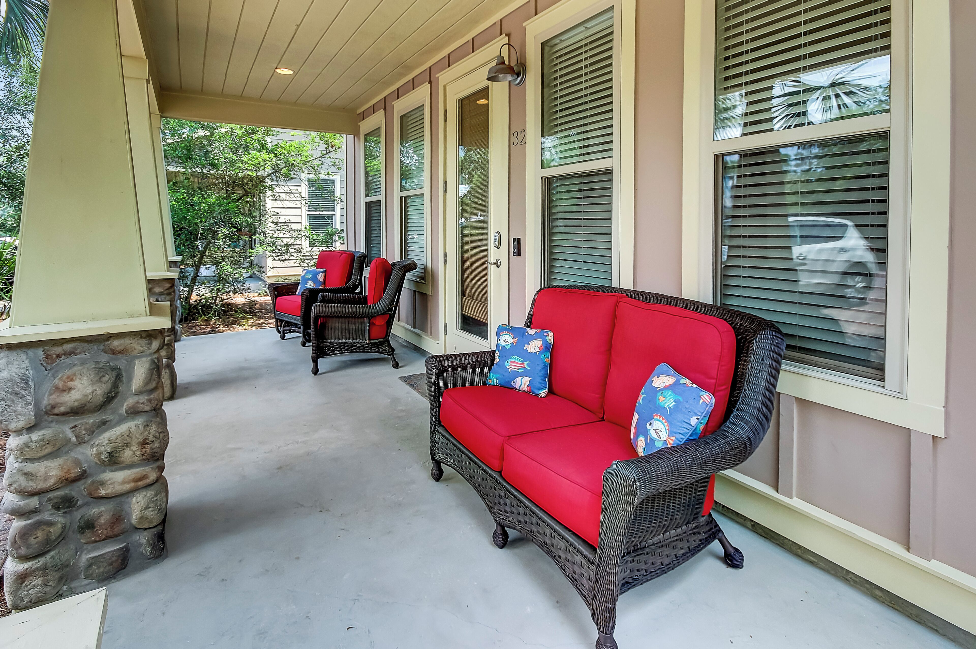 A covered porch with wicker furniture and a stone pillar.