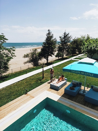 Una piscina al aire libre, sombrillas, sillones reclinables de piscina