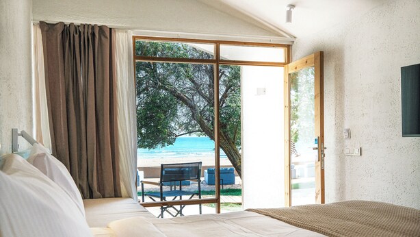 A bedroom with a large bed, a view of the beach, and a sliding glass door leading to an outdoor seating area. - Nayu Igneada (Demirköy)
