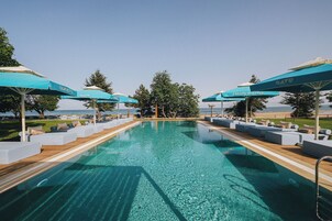 Una piscina al aire libre, sombrillas, tumbonas