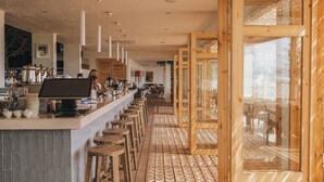 A long bar area with stools, a counter with kitchen equipment, and large windows. - Nayu Igneada (Demirköy)