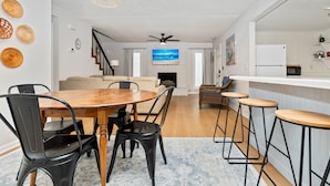 Un espacio habitable moderno con comedor, cocina y una escalera que conduce a otro nivel.
