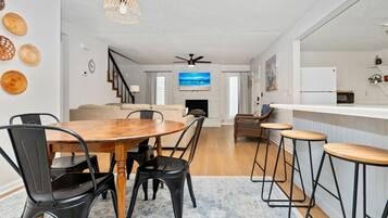 A modern living space with a dining area, kitchen, and a staircase leading to another level.