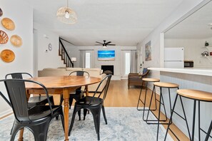 A modern living space with a dining area, kitchen, and a staircase leading to another level.