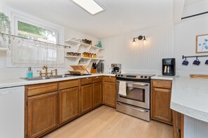 A kitchen with wooden cabinets, a stainless steel stove, and a coffee maker.