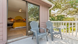 Una habitación con cama, ventilador de techo y vista al exterior.