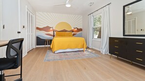 Un dormitorio con cama, escritorio, silla, cómoda y ventilador de techo.