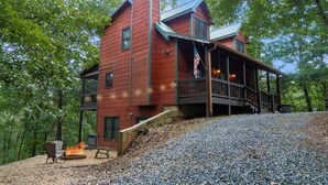 Une cabane rustique avec une façade en bois, une véranda et un foyer extérieur.