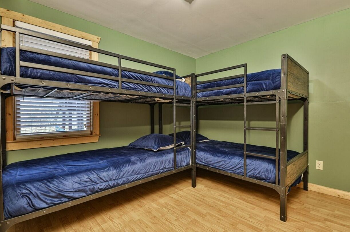 A bunk bed room with green walls and wooden flooring.