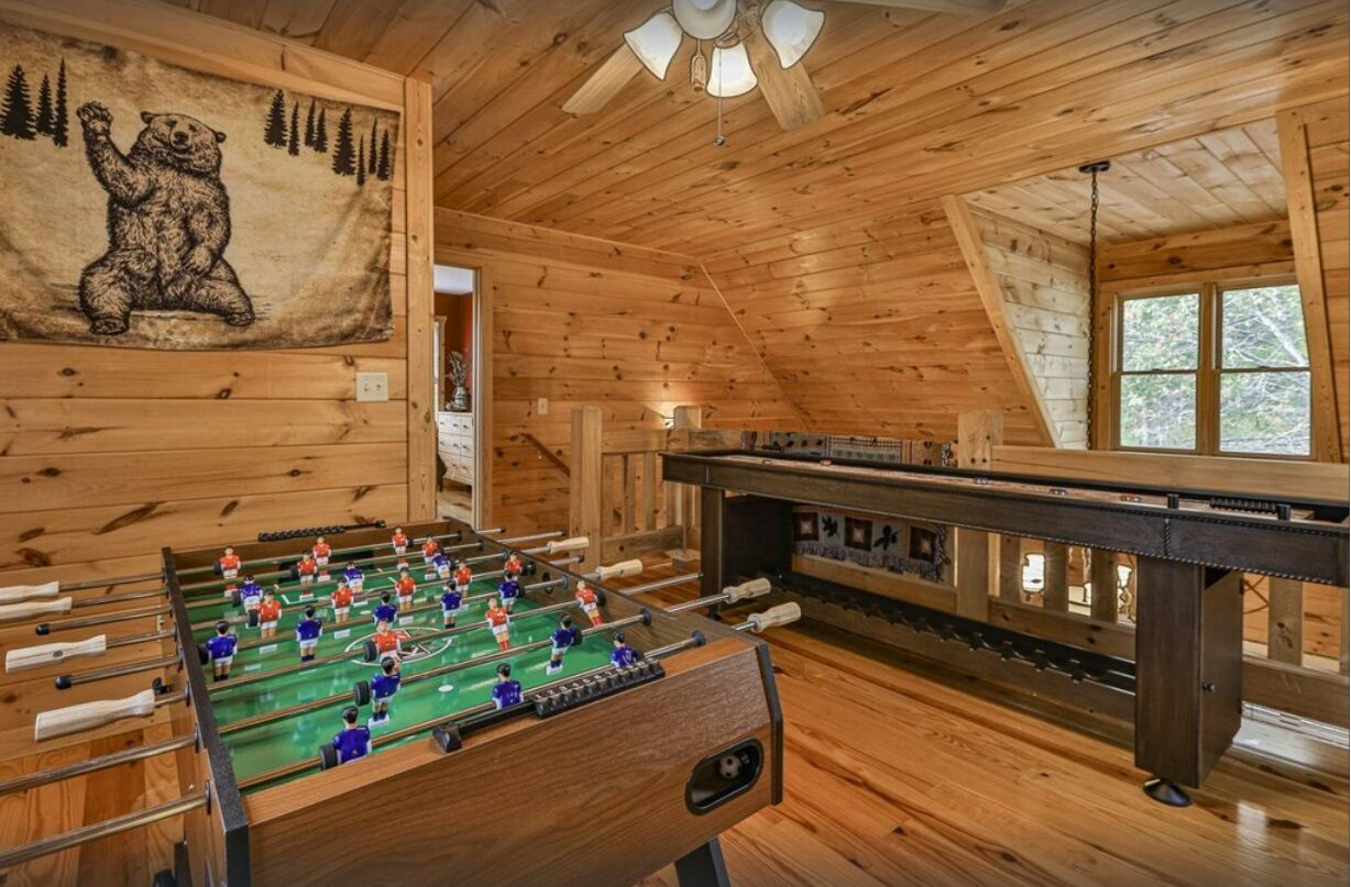 Ein Zimmer mit Holzboden, einem Tischkicker und einer Bärenmalerei.
