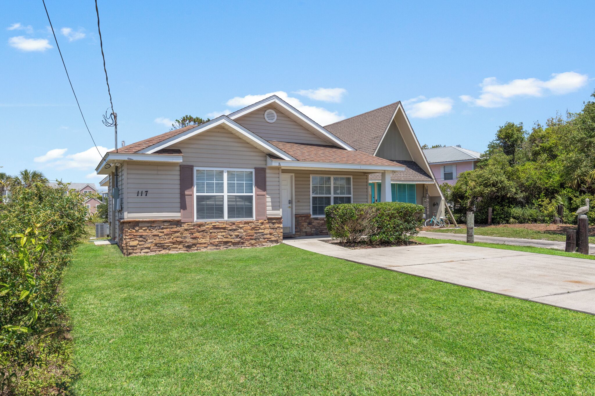 A single-story house with a stone foundation, a pitched roof, and a well-maintained lawn.