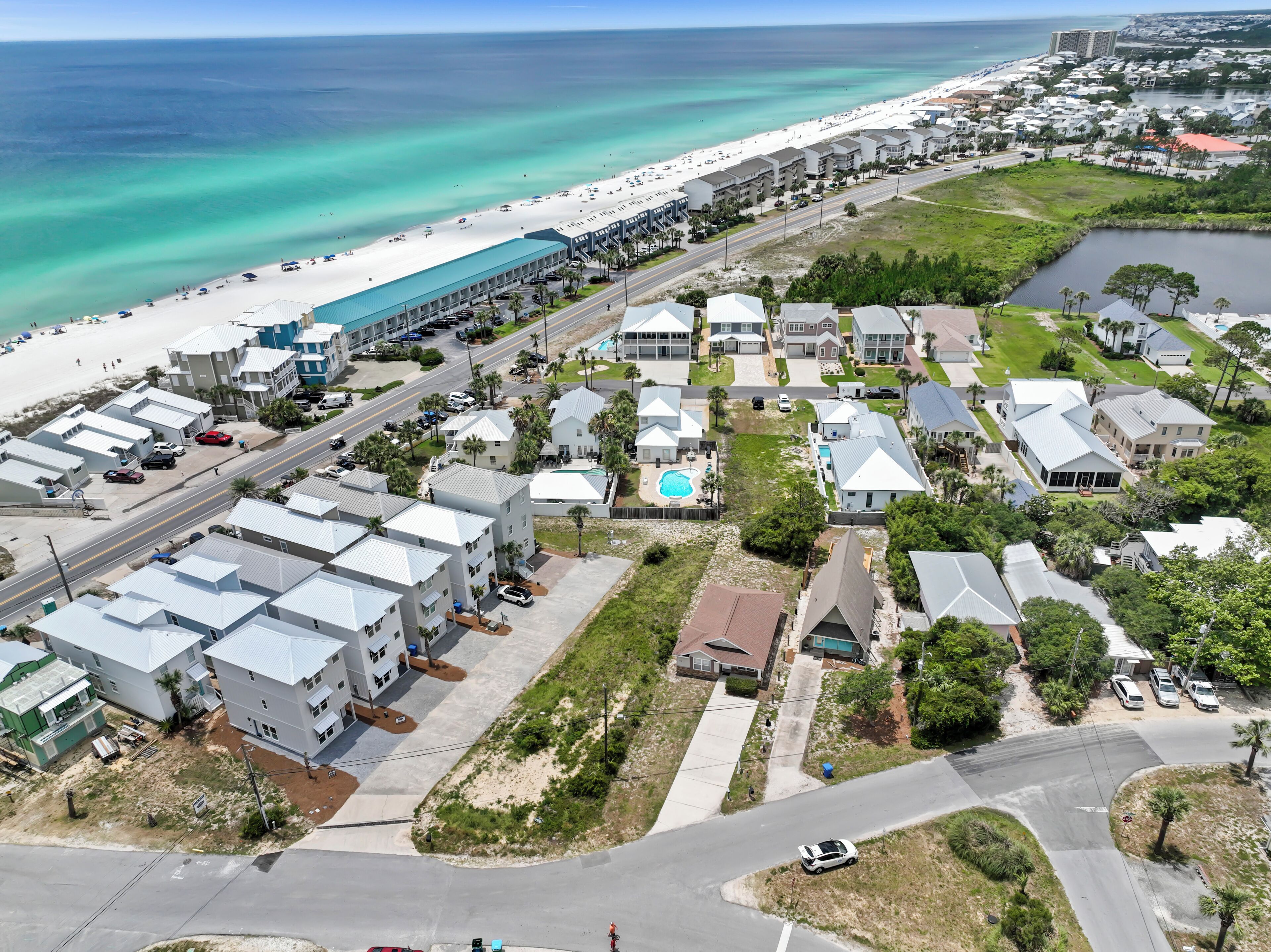 Vista aérea de una zona residencial costera con propiedades frente al mar, una carretera y una playa.