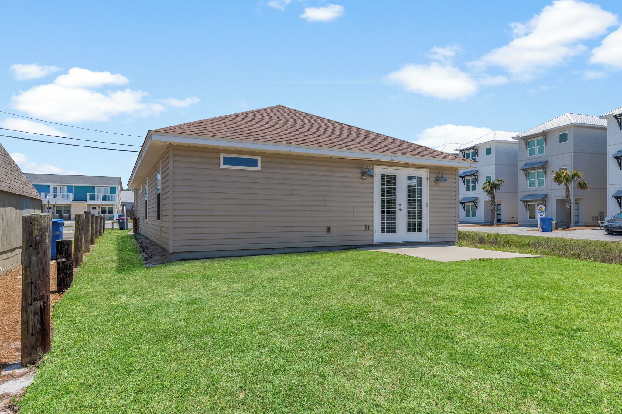 A single-story house with a brown roof and beige siding, a front door, and a small front yard with grass.