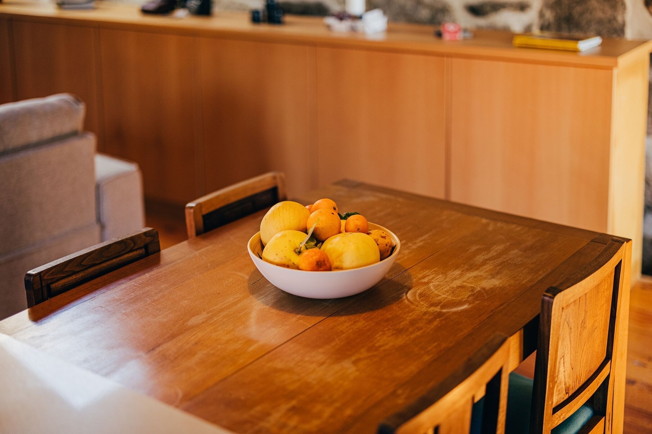 Una mesa de comedor de madera con un cuenco de fruta en el centro.