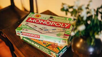 A Monopoly board game on a wooden table with a vase of flowers in the background.