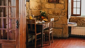 A rustic dining area with a stone wall, wooden furniture, and a tiled floor.