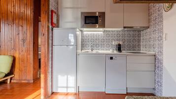 A compact kitchen with a built-in microwave, a refrigerator, and a dishwasher.