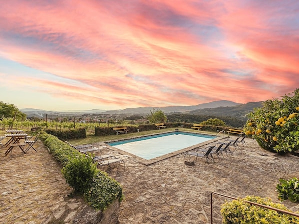 A pool area with lounge chairs and a view of the countryside.