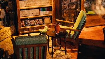 A cozy reading nook with a wooden bookshelf, a green upholstered chair, and a small table with a vase.