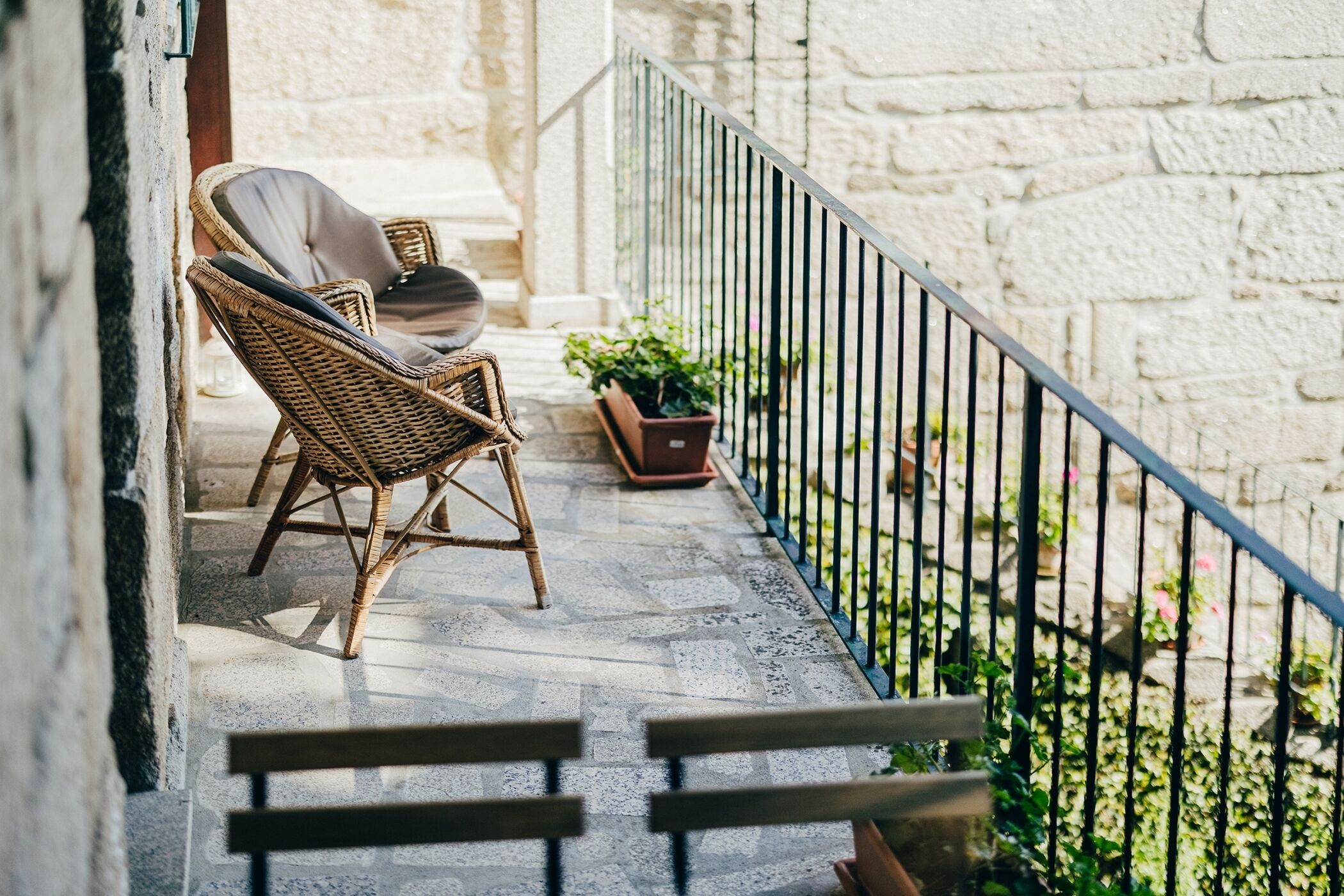 A balcony with wicker chairs and a potted plant.