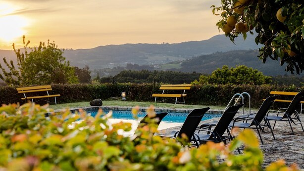 A pool area with lounge chairs and a view of hills in the background. - Quinta Stº António | Palheiro B | Monção | Rural Tourism | Pool (Monção)