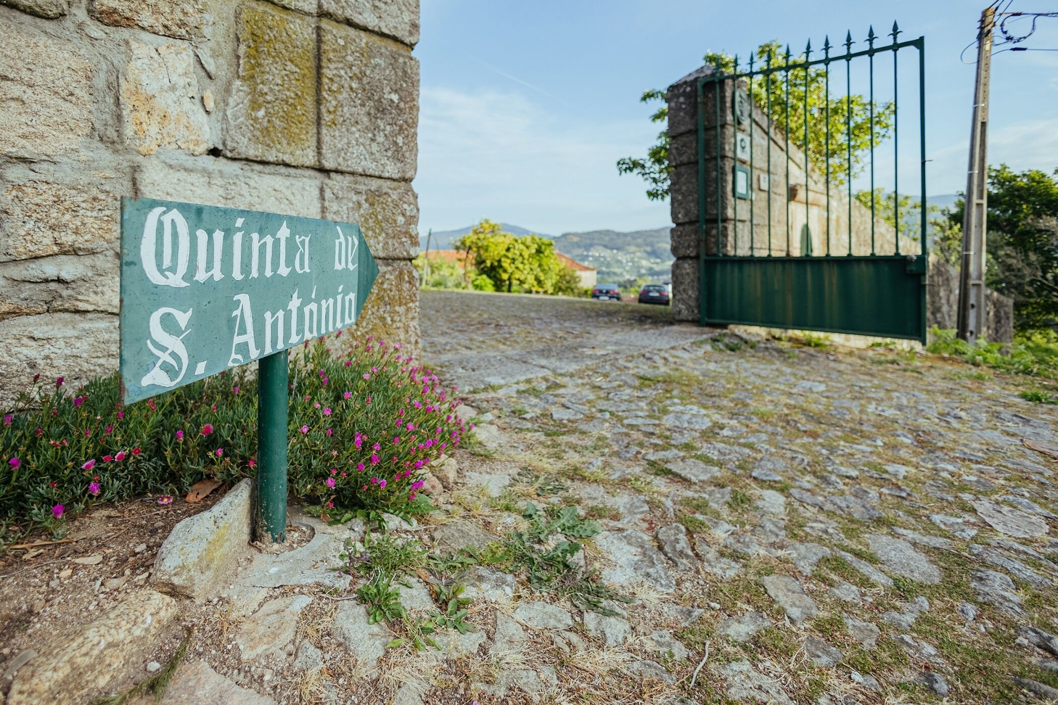 Ein Kopfsteinpflasterweg führt zu einem verschlossenen Eingang mit einem Schild, auf dem "Quinta de S. António" steht.
