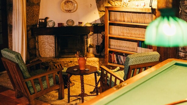 Ein gemütliches Zimmer mit Billardtisch, Kamin und Bücherregal.