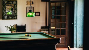 A pool table with balls, a hanging green light fixture, and a door with glass panels. - Quinta Stº António | Palheiro B | Monção | Rural Tourism | Pool (Monção)